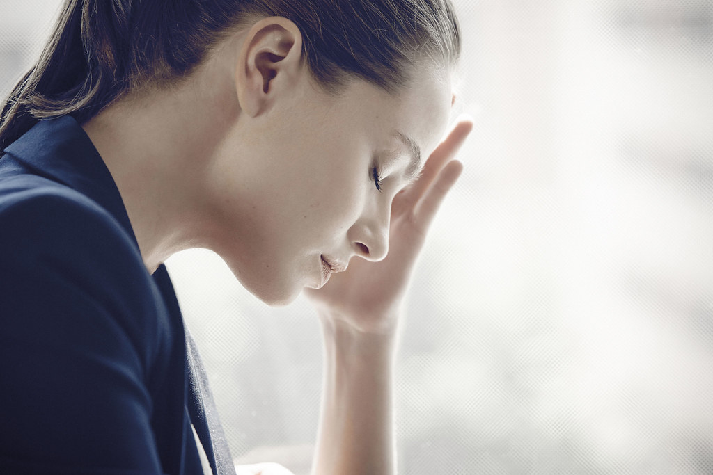 I woman looking frustrated holds her hand to her forehead.