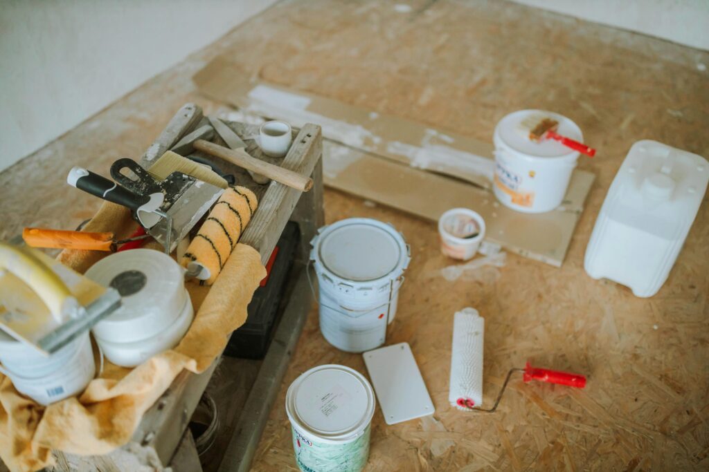 Building Materials, Paint Brushes, Etc... sit on the floor of a room being renovated.