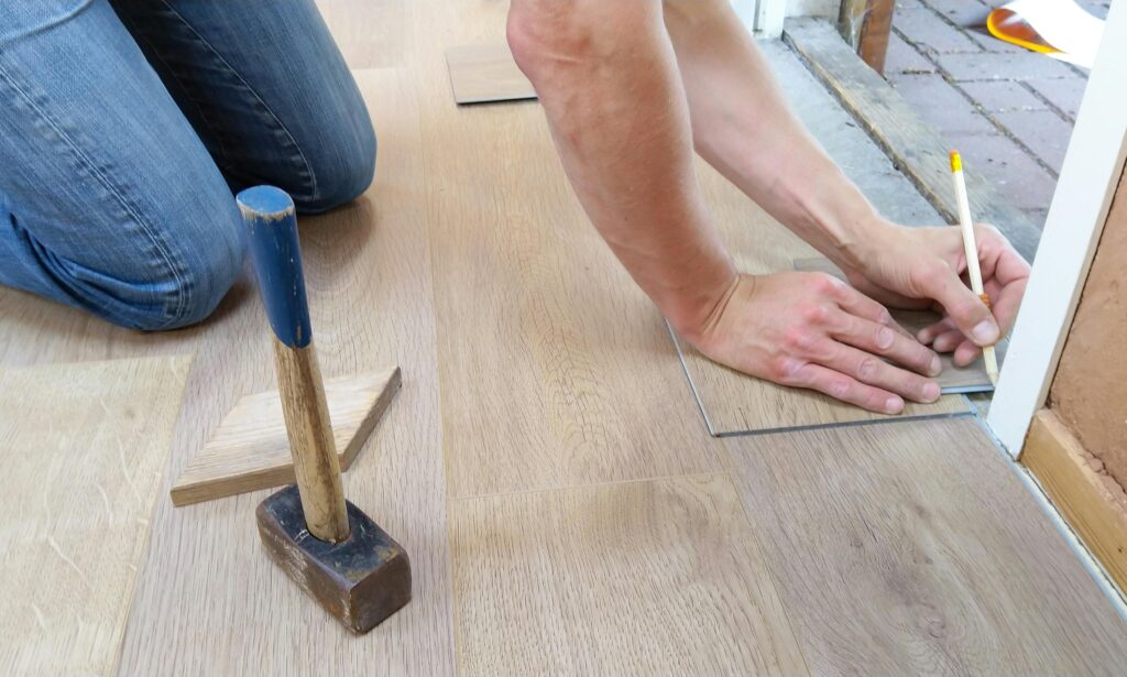 A Person in the threshold of a doorway measures the flooring to be installed.