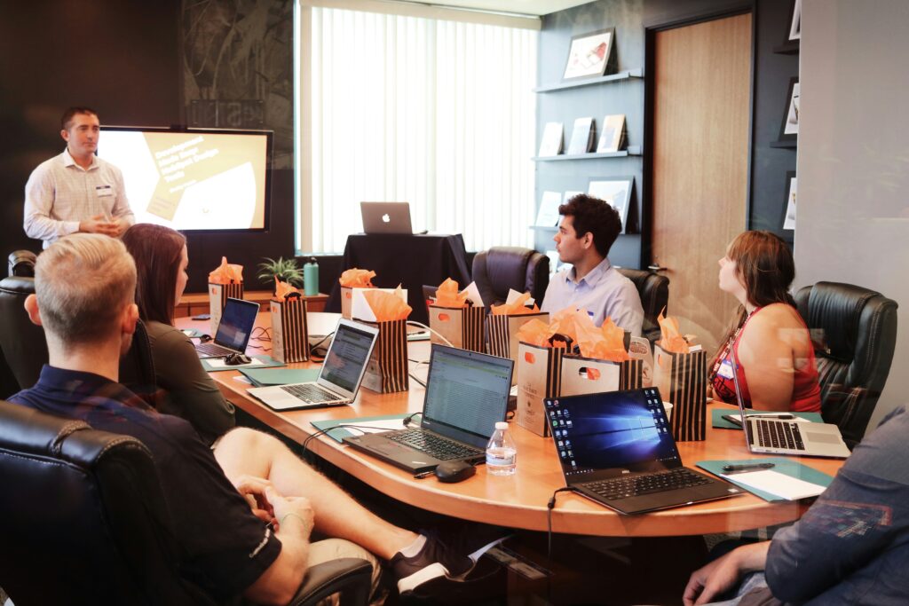 A conference room of workers listen to their boss.